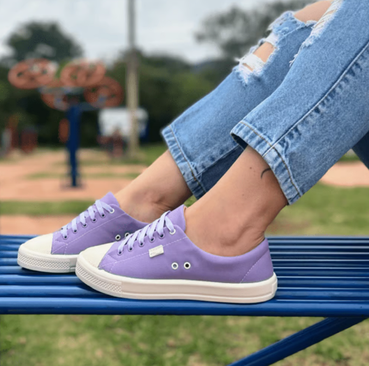 Moça mostrando seu tênis de lona lilás Tenis de lona